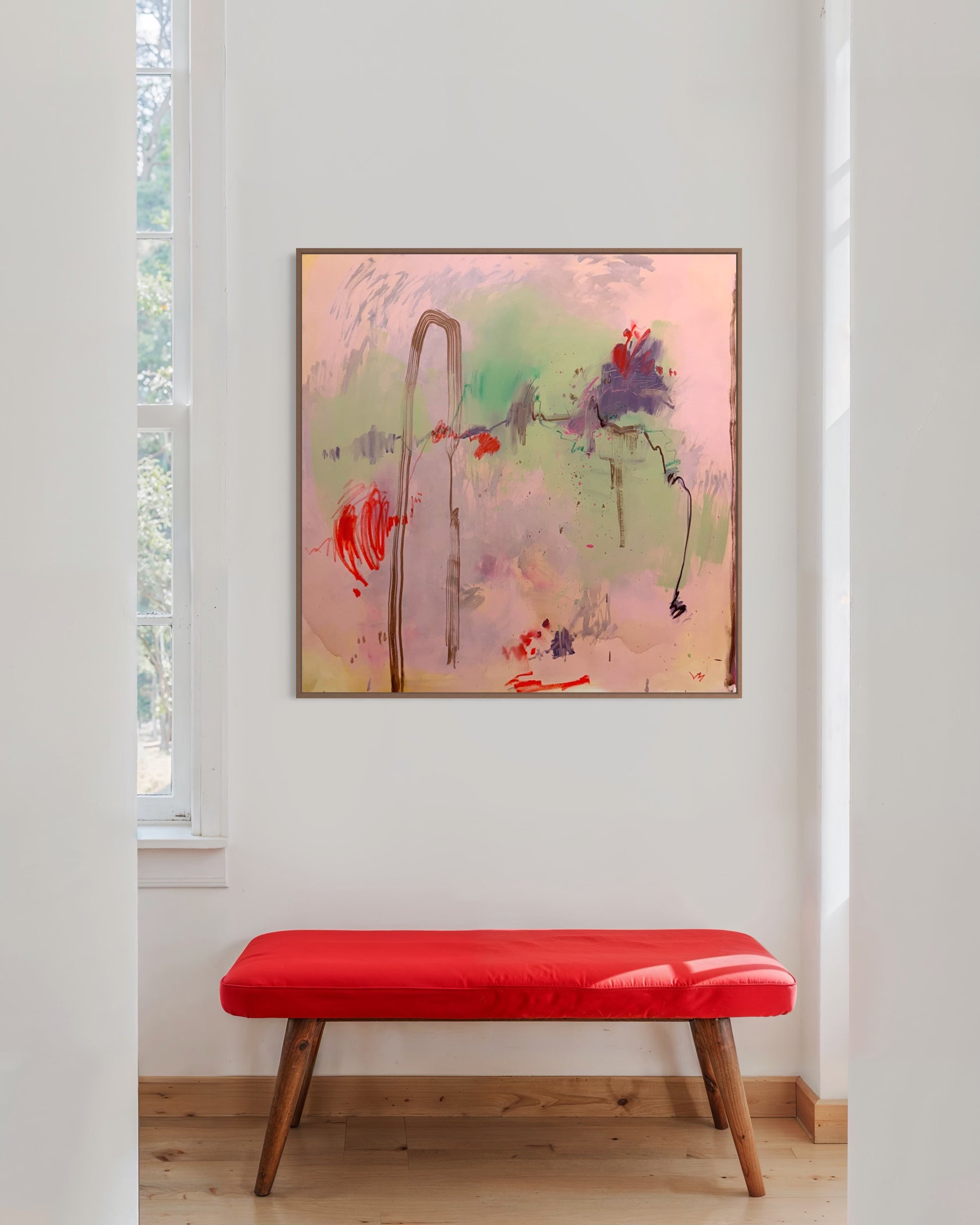 Abstract painting on a wall above a red bench in a room with a window.
